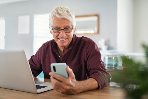 Man using laptop and smartphone simultaneously